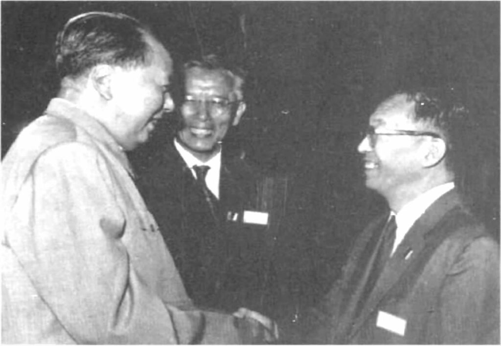 毛泽东与日本代表团团长坂田昌一握手，双方展现友好氛围，背景模糊。