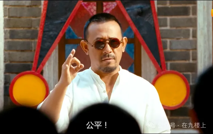 一名男子穿着白色衬衫和太阳镜，手势示意，背景为彩色几何图形，旁边的人群在注视他。