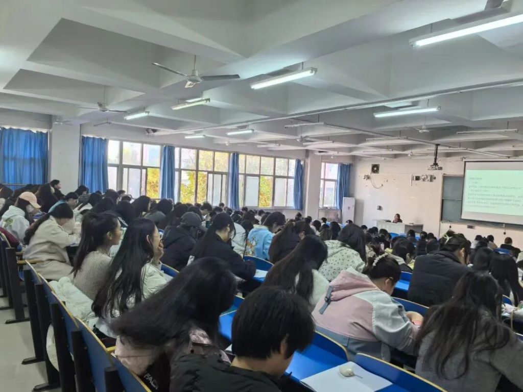 教室内学生专注听课，黑板上显示课程内容，窗外阳光透入，环境明亮